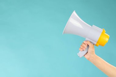 Mavi arka planda megafon hoparlörü tutan kadın, yakın plan. Metin için boşluk