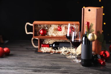 Bottles of wine, glasses, wooden boxes, fir twigs and Christmas balls on table