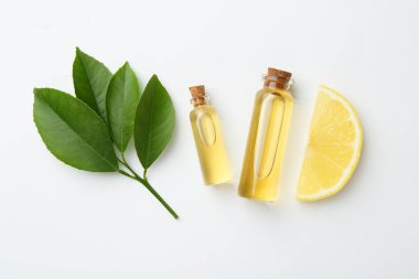 Beyaz arka planda gerekli yağlar, limon ve yeşil yapraklar.