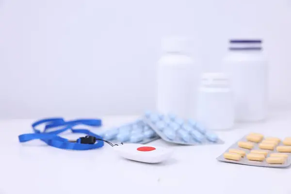 stock image Emergency call button and pills on white table