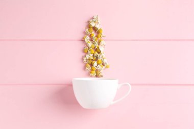 Papatya çiçekleri ve beyaz bardak pembe ahşap masa, üst manzara