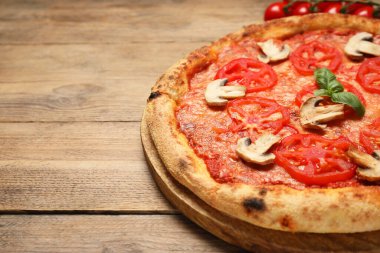 Domatesli, mantarlı ve ahşap masadaki fesleğenli lezzetli pizza, yakın plan. Metin için boşluk
