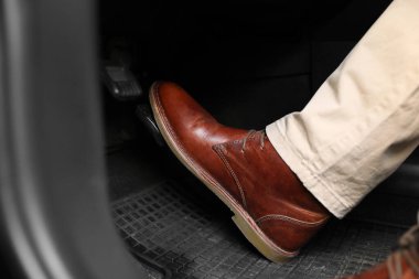 Man pushing on pedal of car brake, closeup clipart