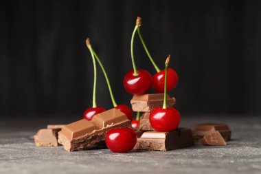 Gri desenli masada sütlü çikolatalı taze kirazlar, yakın plan.