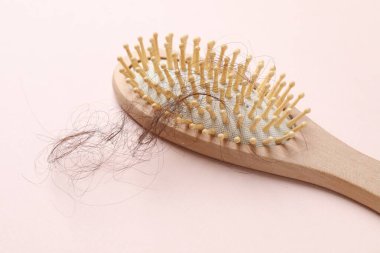 Açık pembe arka planda saçlarını kaybetmiş bir fırça. Alopecia sorunu