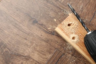 Kablosuz elektrik matkabı, tahta ve talaş, ahşap masa, üst manzara. Metin için boşluk