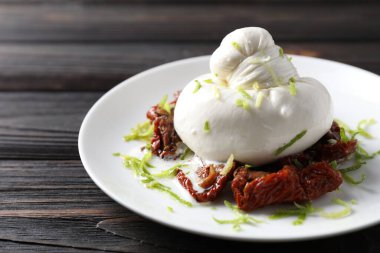 Lezzetli burrata peyniri ve kurutulmuş domatesler ahşap masada, yakın plan.