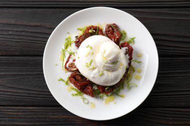Lezzetli burrata peyniri ve kurutulmuş domatesler ahşap masada, üst manzara