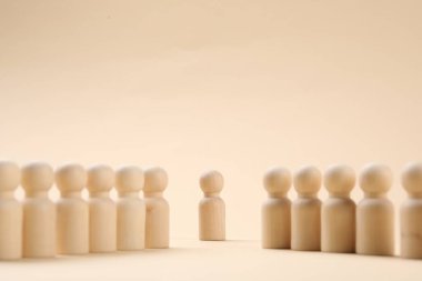 Loneliness concept. Human figure alone among others on beige background