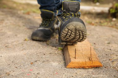 Dikkatsiz işçiler tahta çiviye basıyor, yakın plan.