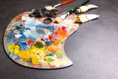 Sanatçı paleti, gri masada fırçalar ve boyalar, metin için boşluk