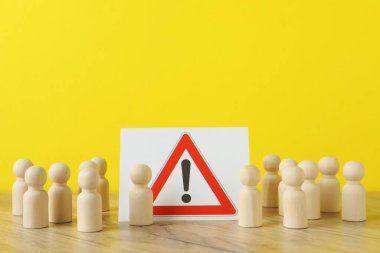 Tahta insan figürleri sarı arka plana karşı uyarı tabelaları arasında