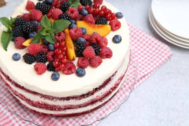 Farklı meyveli lezzetli sünger kek ve açık gri masada nane şekeri, yakın plan.