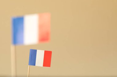 Bej arka planda Fransa 'nın küçük kağıt bayrakları, seçici odaklanma. Metin için boşluk