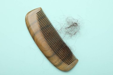 Açık mavi arka planda saçı dökülmüş bir tarak, üst manzara. Alopecia sorunu