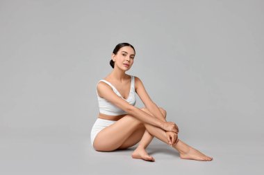 Gri arka planda iç çamaşırlı, mükemmel ciltli güzel bir kadın. Vücut bakımı