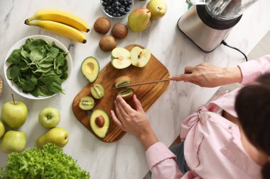 Mutfaktaki beyaz mermer masada blender ile nefis smoothie yapan kadın.