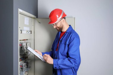 Elektrik sayacını incelemek için pano kullanan teknisyen.