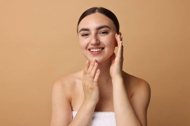 Yüz masajı. Bej arka planda sağlıklı cilde sahip güzel genç bir kadın.