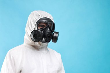 Açık mavi arka planda, düşük açılı gaz maskeli bir işçi. Metin için boşluk