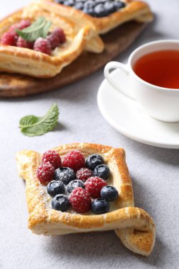 Böğürtlenli börekler ve beyaz masada çay, yakın plan.