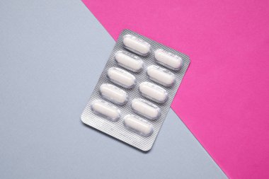 Renkli arka planda su toplayan antibiyotik haplar, üst görünüm