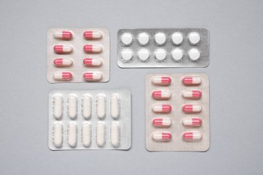 Gri arka planda kabarcıklarda farklı antibiyotik hapları var.