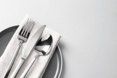 Beyaz arka planda gümüş çatal bıçak, tabak ve peçete, üst manzara. Metin için boşluk