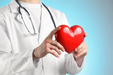 Açık mavi arka planda kırmızı kalpli doktor, yakın plan.
