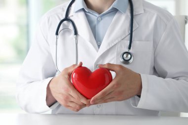 Klinikteki beyaz masada kırmızı kalpli doktor, yakın plan.