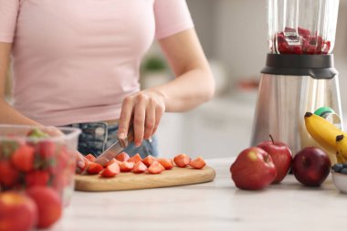 Mutfaktaki beyaz mermer masada blender ile nefis smoothie yapan kadın, yakın plan.