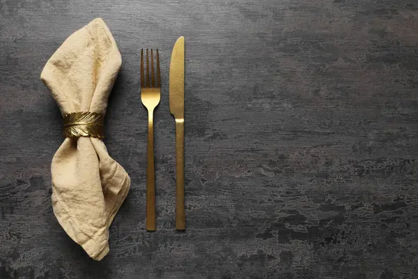 Gri masa üzerinde şık çatal bıçak takımı ve peçete, üst manzara. Metin için boşluk