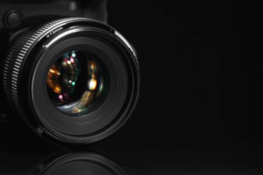 Siyah ayna yüzeyinde modern bir fotoğraf makinesi, yakın plan. Metin için boşluk