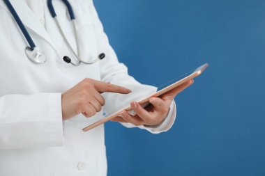 Mavi arkaplanda tableti olan doktor, yakın plan görünümü