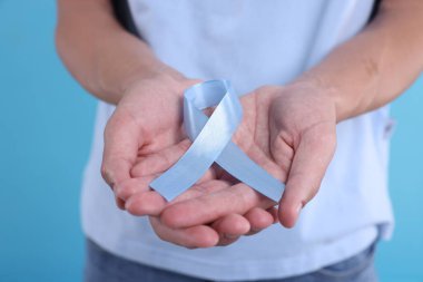 Prostat kanseri farkındalığı. Açık mavi kurdele tutan adam renk arkaplanındaki desteğin sembolü, yakın plan