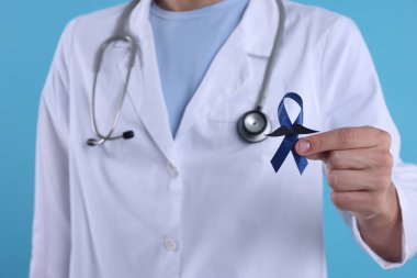 Prostat kanseri farkındalığı. Doktor elinde sahte bıyıklı mavi kurdele tutuyor.
