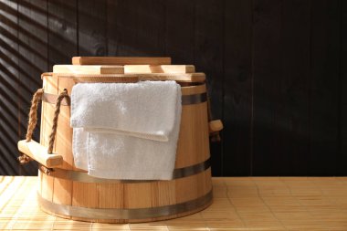 Sauna ekipmanları. Bambu tezgahında kova ve havlu, metin için yer