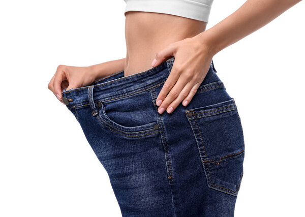 Diet and weight loss concept. Woman in big jeans showing her slim body on white background, closeup