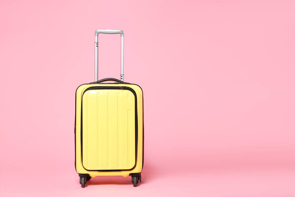 One new yellow suitcase on pink background, space for text