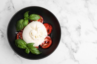 Lezzetli burrata peyniri, domates ve fesleğen beyaz mermer masa, üst manzara. Metin için boşluk