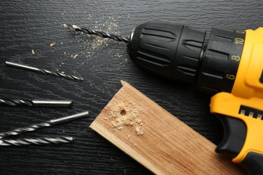 Kablosuz elektrik matkabı, tahta parçaları, siyah ahşap masa, yukarıda.