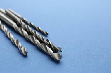 Açık mavi arka planda birçok farklı matkap ucu, yakın plan. Metin için boşluk