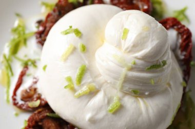 Lezzetli burrata peyniri ve tabakta kurutulmuş domatesler, yakın plan.