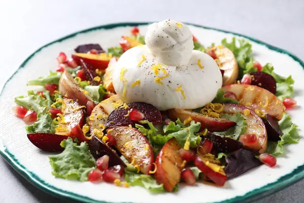 Gri masada taze burrata salatası, yakın plan.