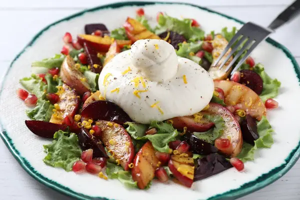 Beyaz ahşap masada taze burrata salatası, yakın plan.