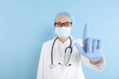 Doktor açık mavi arka planda bir şeye işaret ediyor, seçici odak