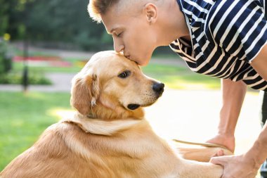 Genç adam parkta sevgili köpeğini öpüyor.