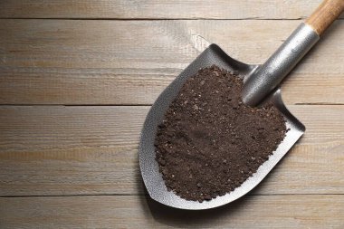 Ahşap masa üzerinde toprak olan metal kürek, üst manzara. Metin için boşluk