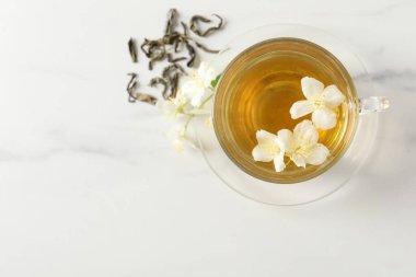 Aromatik yasemin çayı, çiçekler ve kuru yapraklar beyaz mermer masa, üst manzara. Metin için boşluk