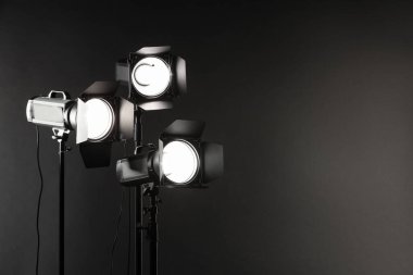 Karanlık fotoğraf arkaplanı ve profesyonel ışıklandırma ekipmanları stüdyoda. Metin için boşluk